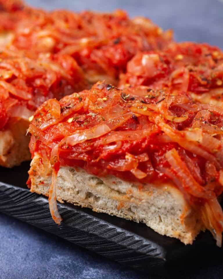 Sicilian pizza on a tray topped with caramelised onions.