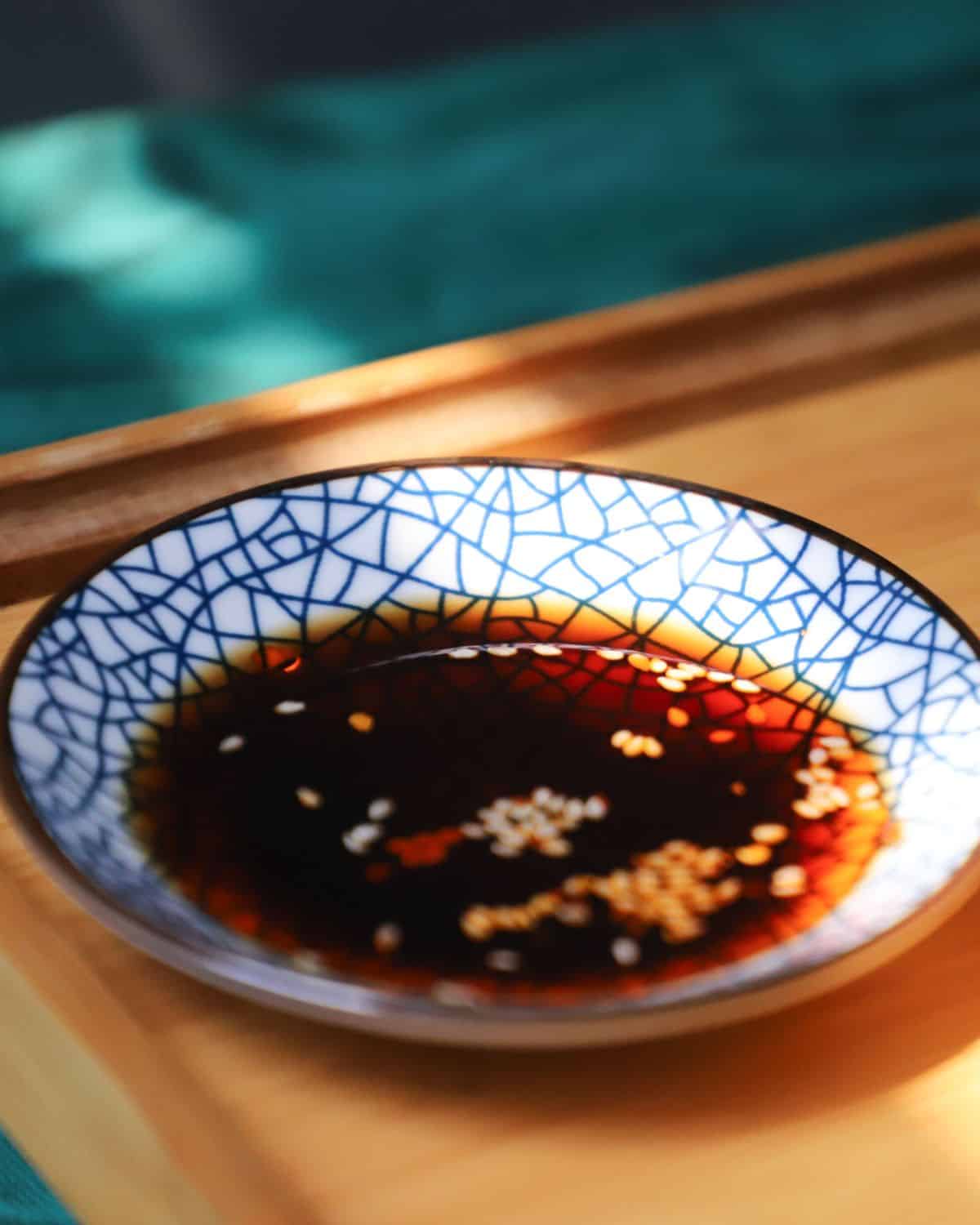 Soy sauce in a bowl with sesame seeds.