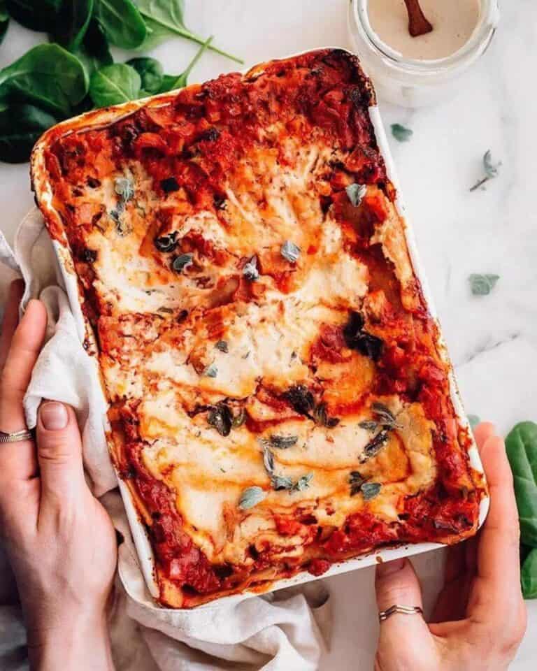 Vegan lasagna in a tray with fresh herbs on top.