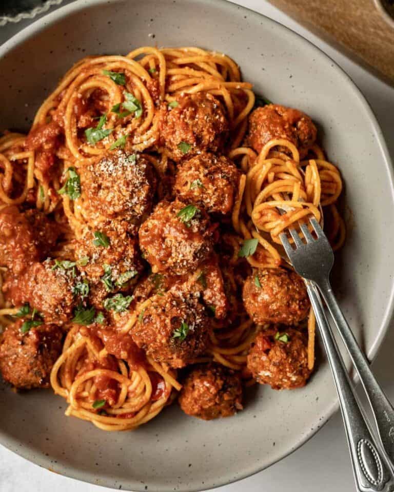 Vegan spaghetti and meatballs topped with vegan parmesan on a plate.