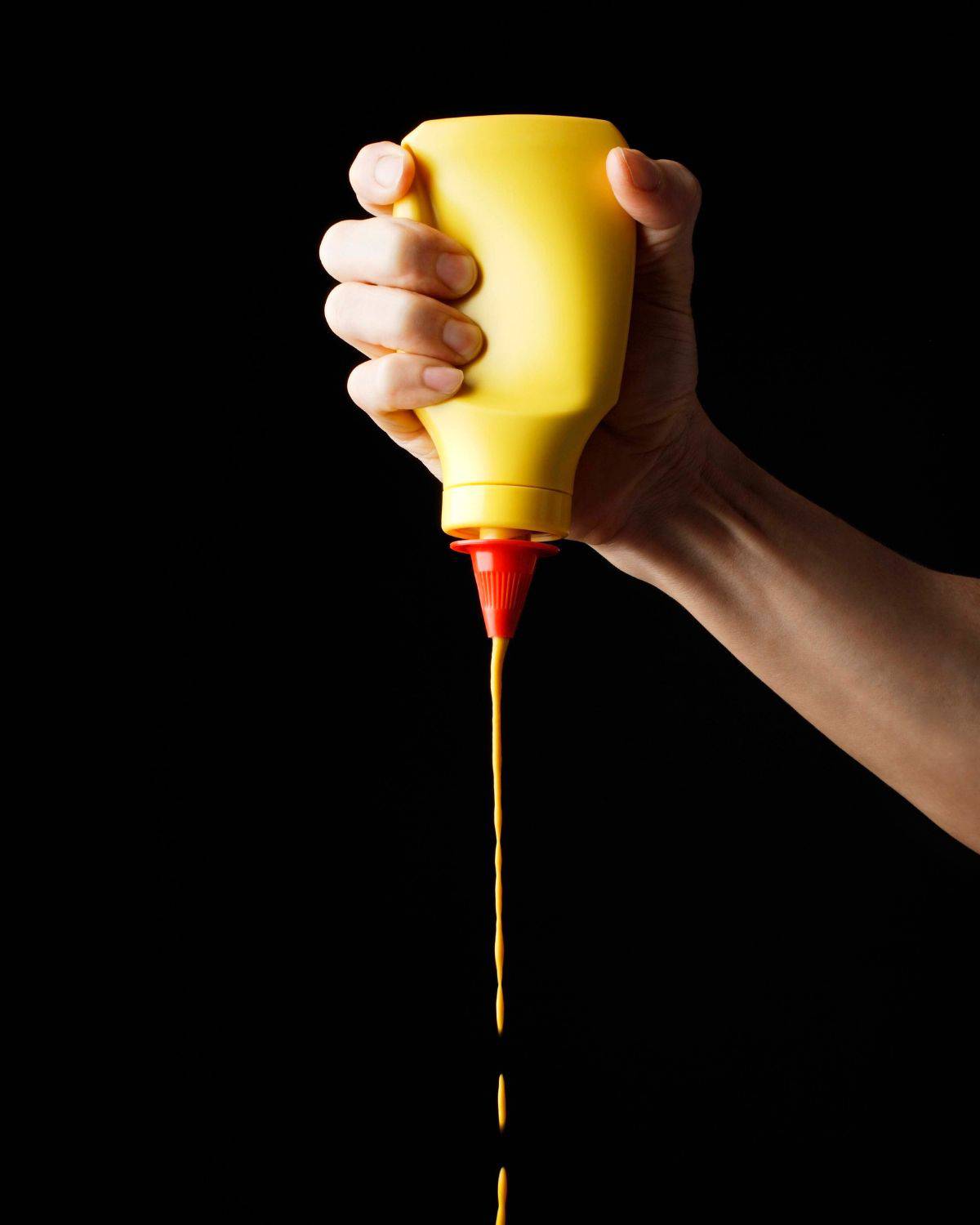 American mustard being squeezed out of a bottle.