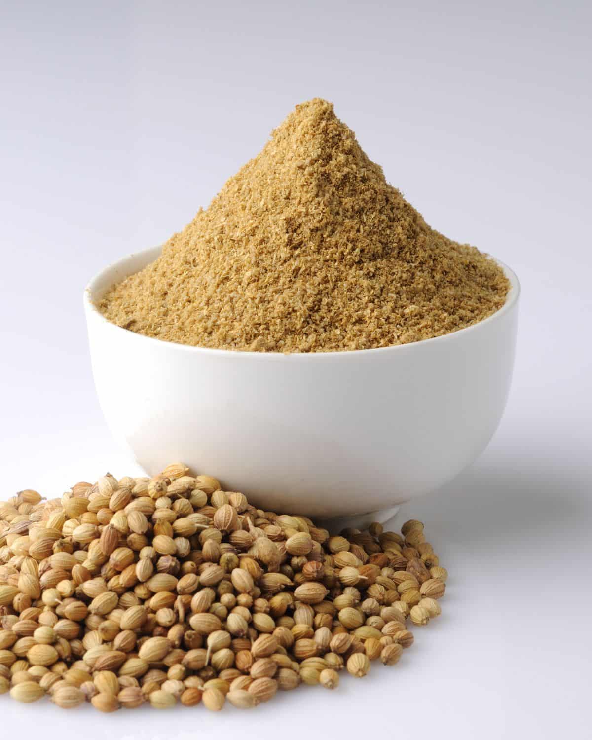 Coriander seeds and powder in a bowl.