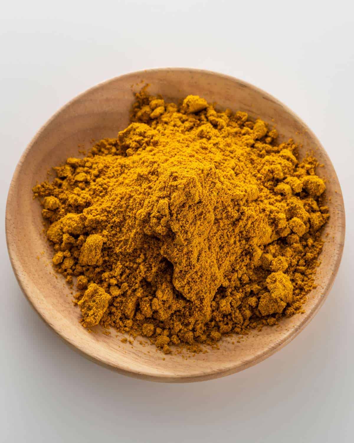 Curry powder piled high in a wooden bowl.
