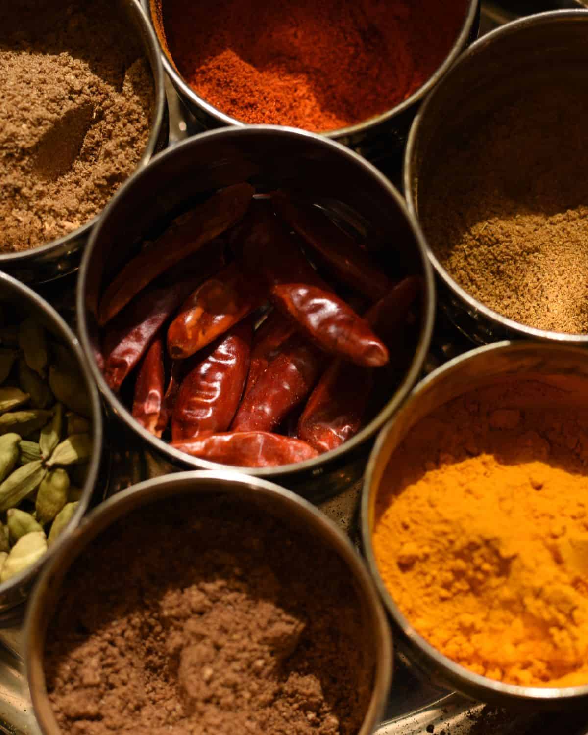 Ground and whole spices and dried chillies in a thali set.