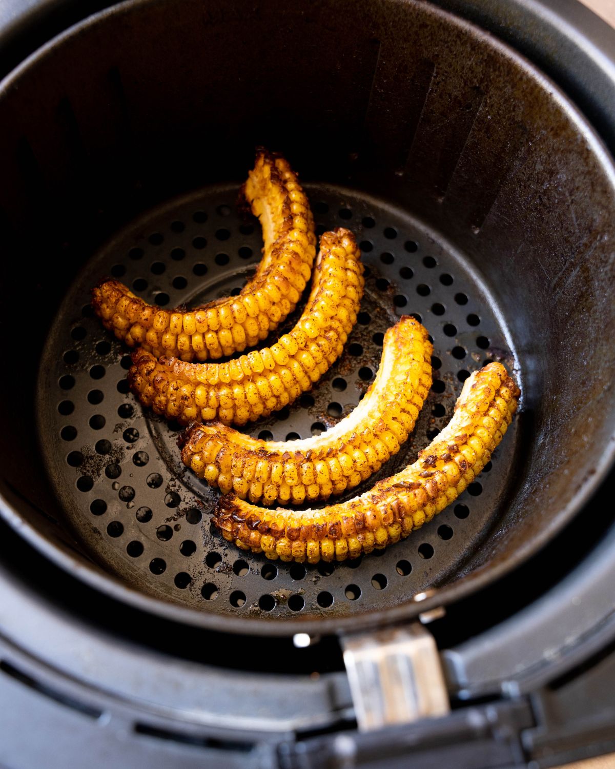 Cooked corn ribs in an air fryer basket.