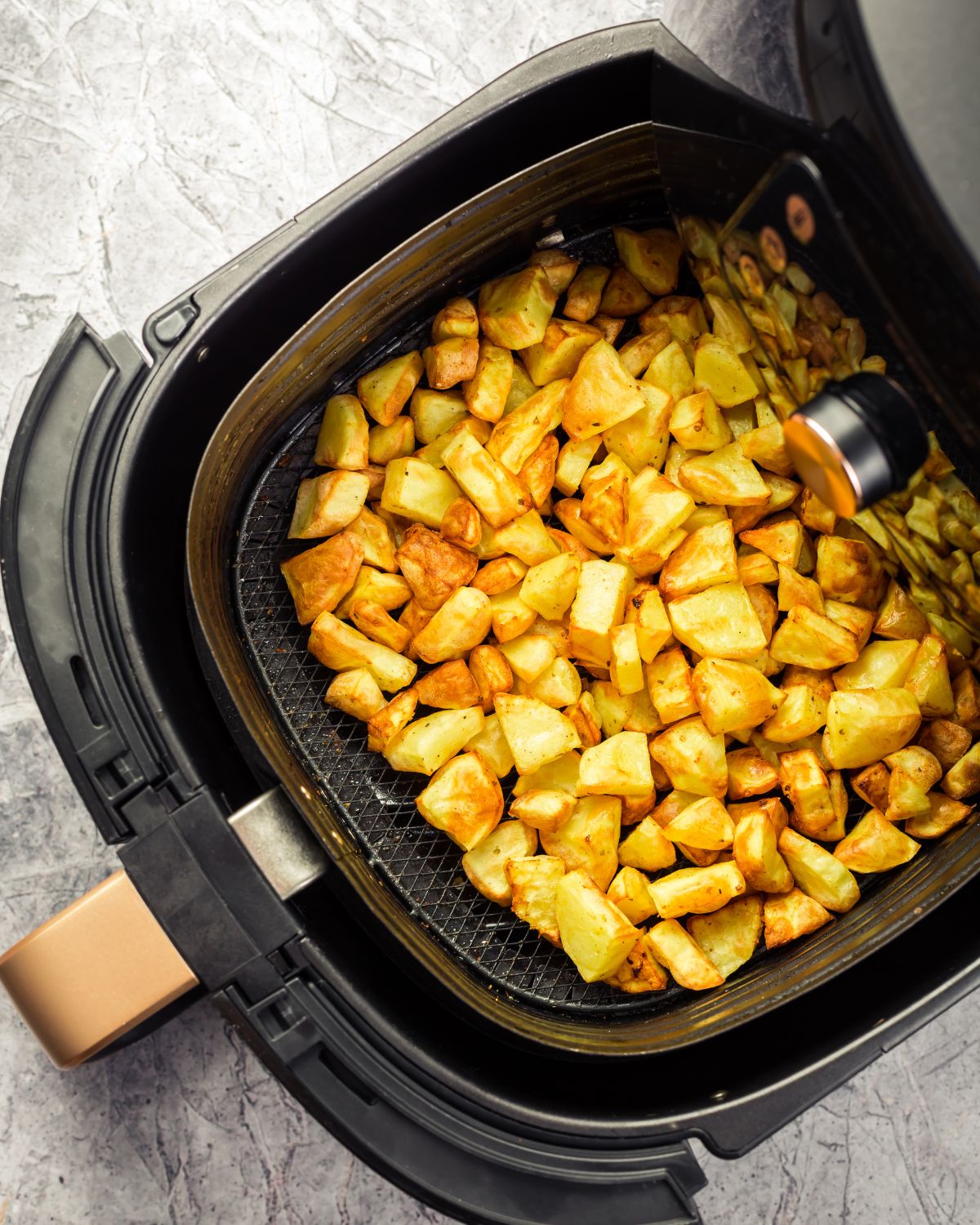 Potatoes in an air fryer basket.