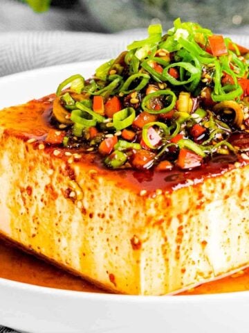 A block of silken tofu with toppings on top.