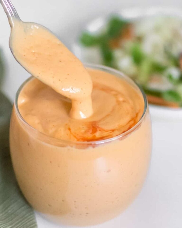 Sriracha dressing in a glass jar with a spoon.