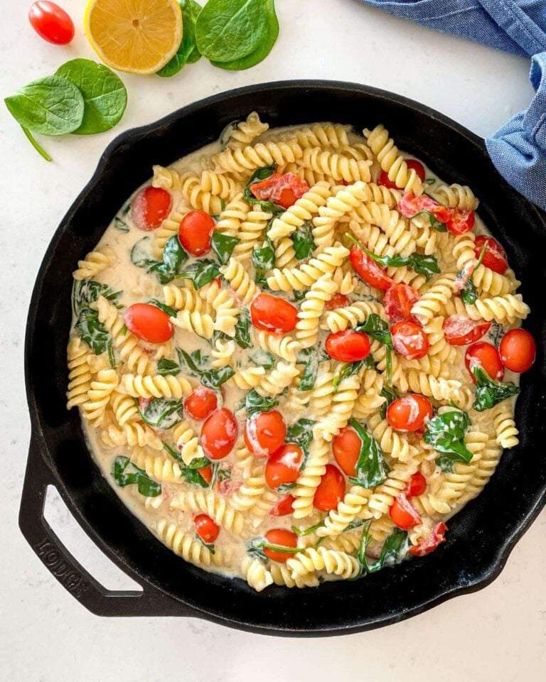 Tofu pasta with cherry tomatoes and spinach in a skillet.