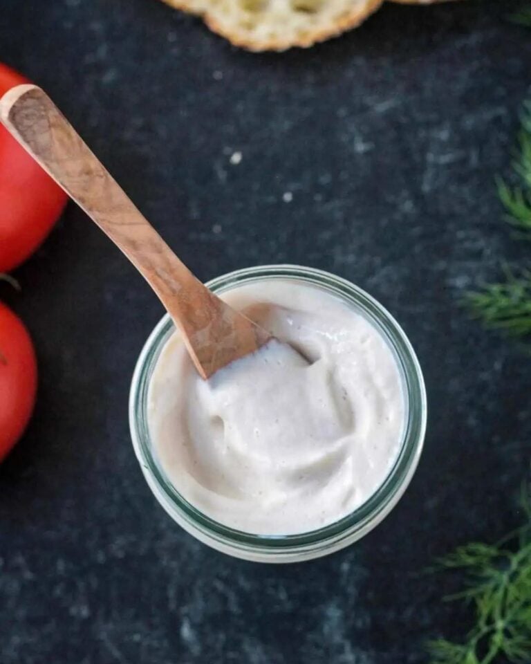 Vegan sour cream in a glass jar with a wooden spoon.