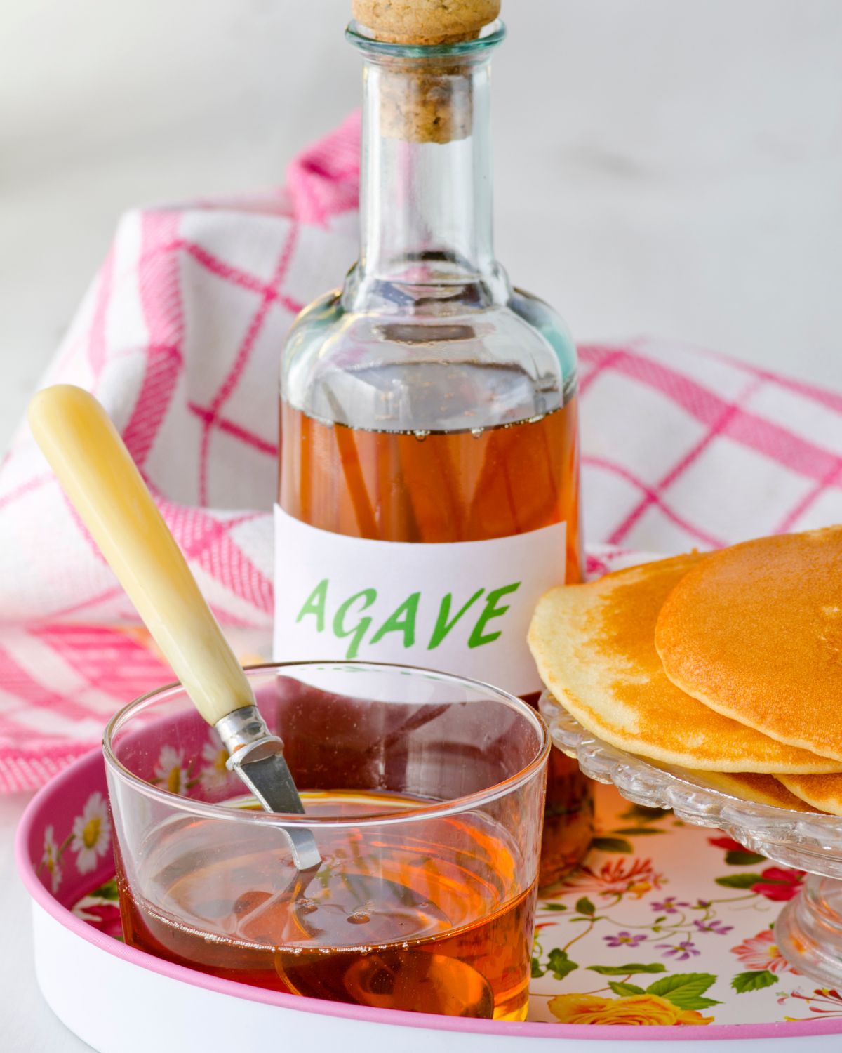 Agave syrup in a bottle next to pancakes.