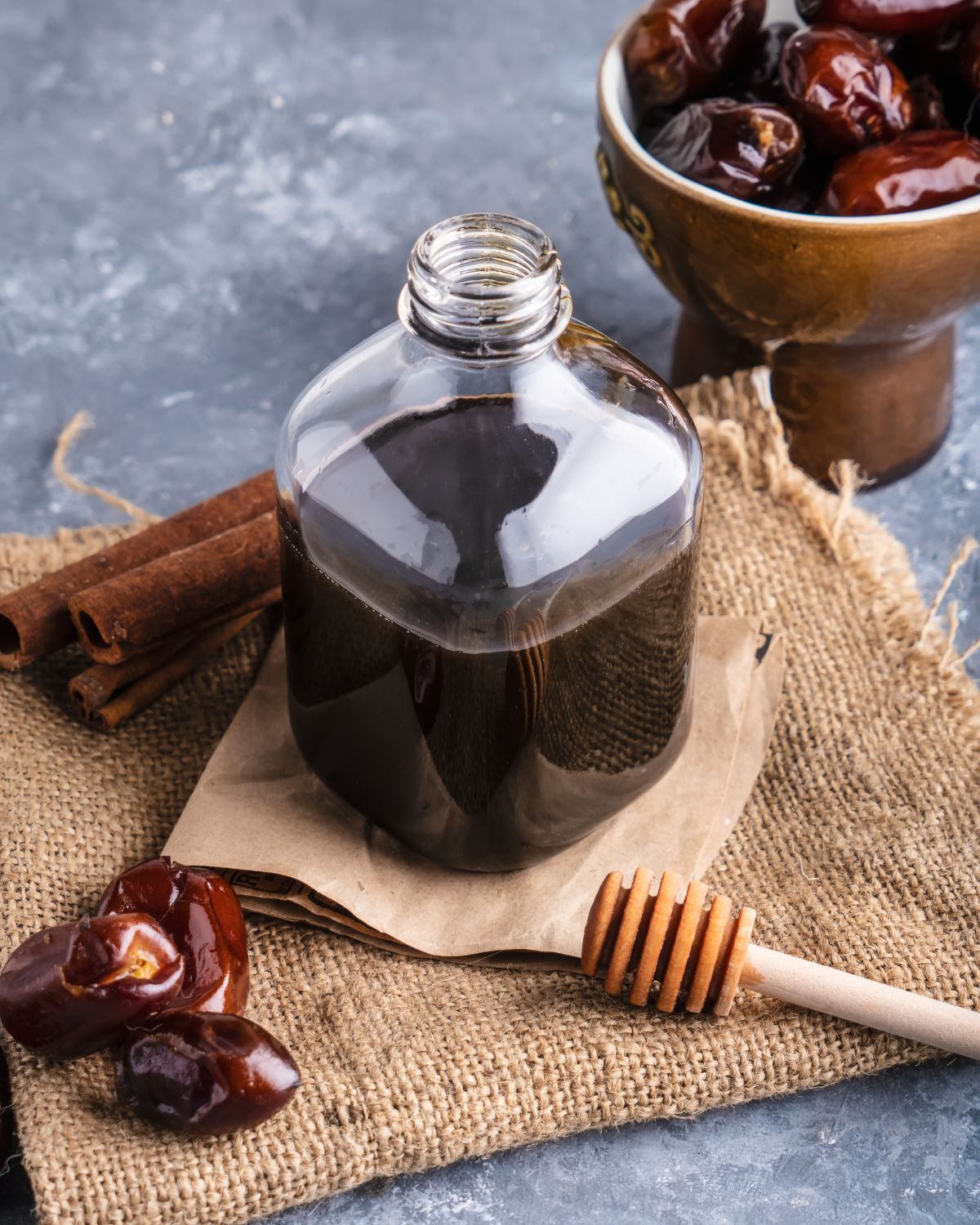 Date syrup in a medicine bottle with dates around it.