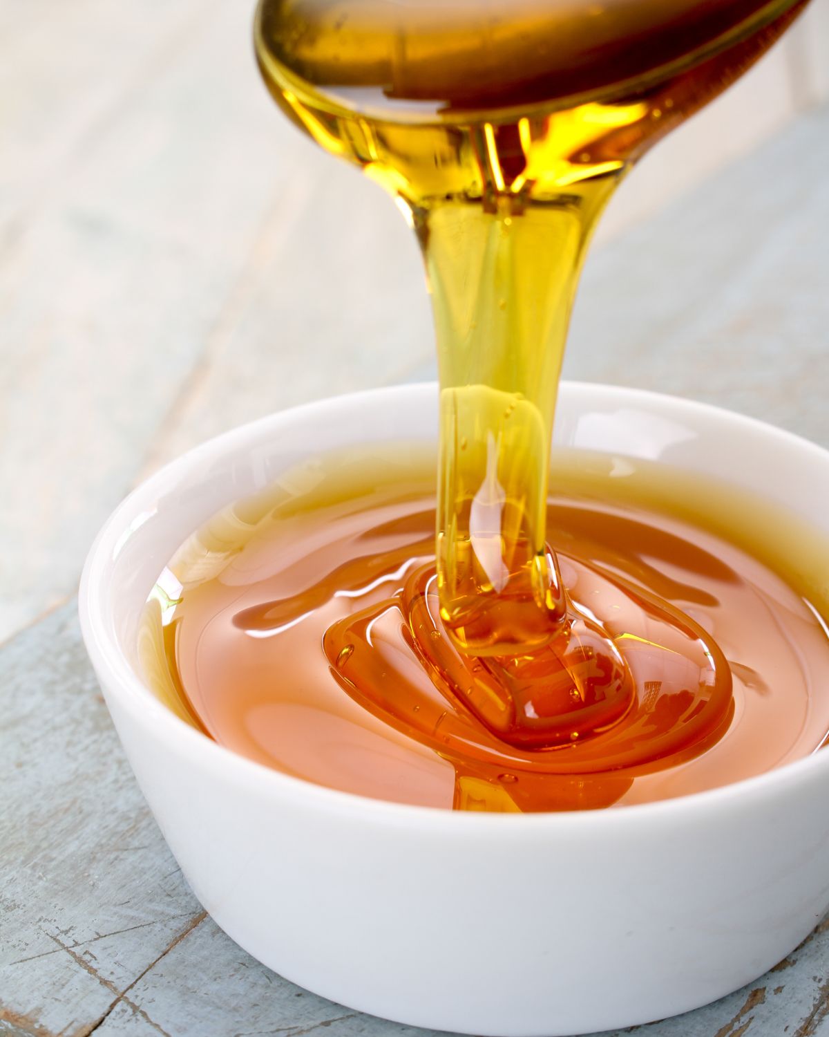 Light molasses coming off a spoon into a bowl.