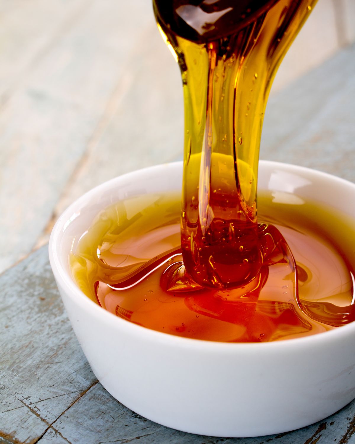 Golden syrup coming off a spoon into a bowl.