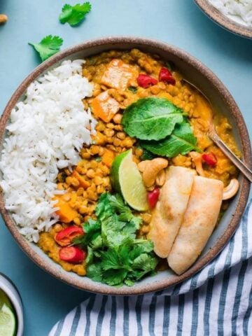 Butternut squash curry in a bowl with bread, lime and coriander.