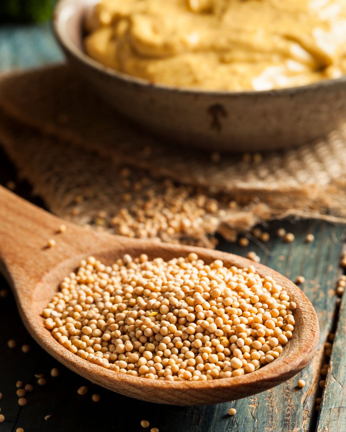 Yellow mustard seeds on a wooden spoon.