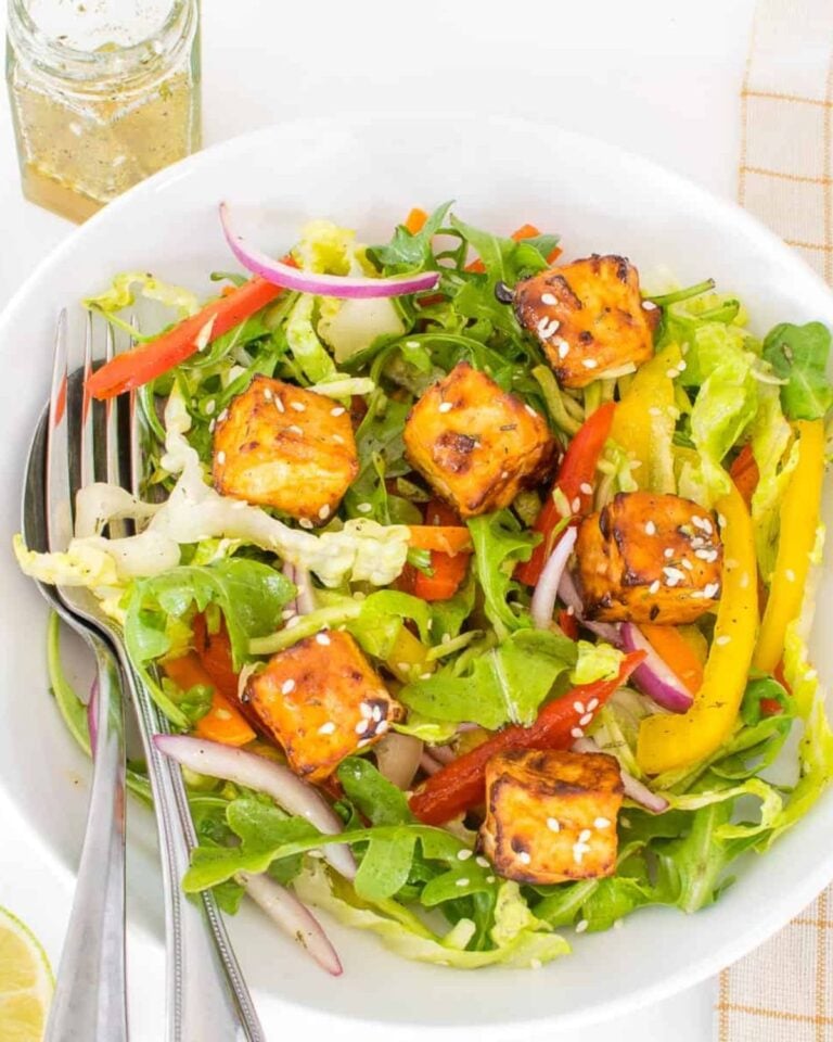 Crispy tofu salad in a bowl with fresh peppers and dressing.