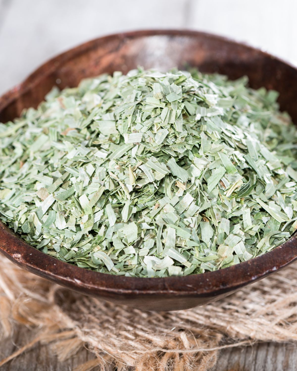 Dried tarragon in a wooden bowl.