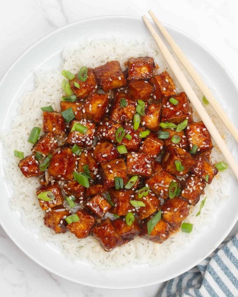 Mongolian tofu served on a bed of rice, topped with sesame seeds and spring onions.