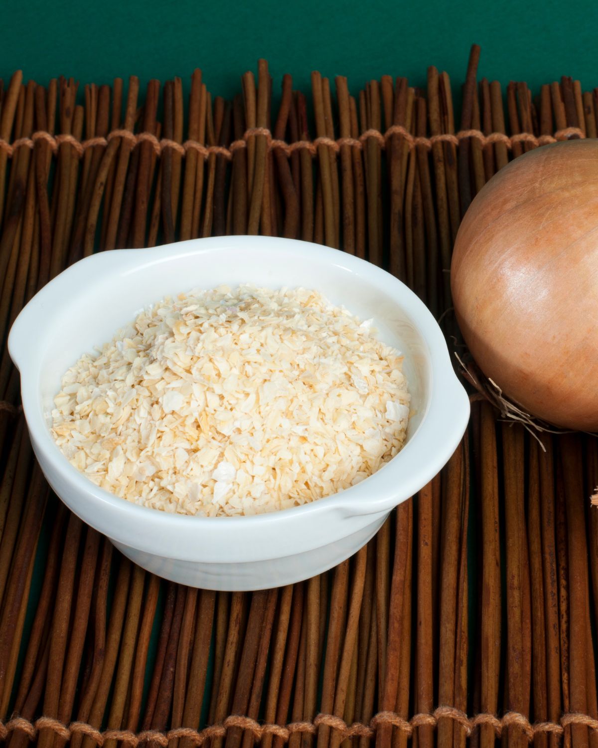 Onion powder in a bowl with an onion next to it.