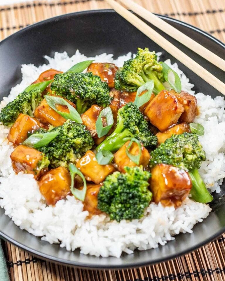 Teriyaki tofu with broccoli and rice, chopsticks balanced on the bowl.