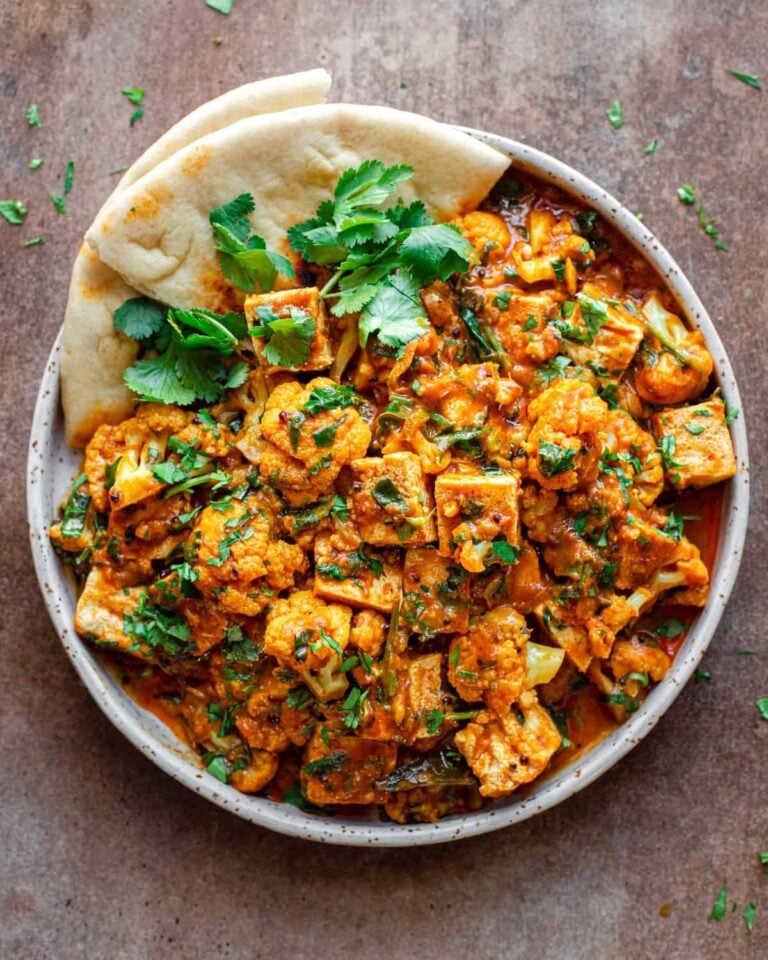 Tofu curry in a bowl with naan bread.