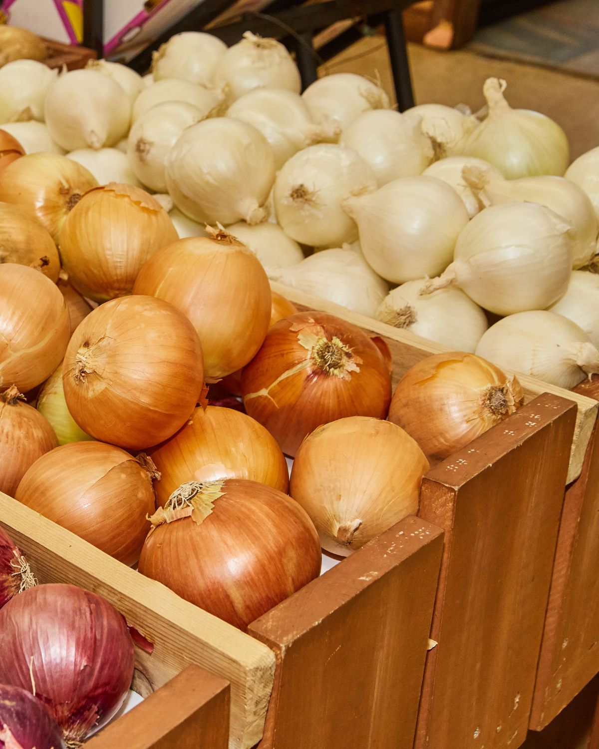 Yellow and white onions in a wooden crate.
